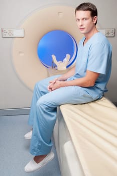 Portrait of a healthcare worker sitting on a CAT scan machine