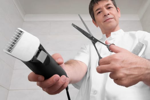 Vet holding an electric razor and scissors