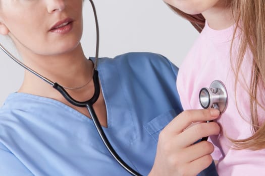 Female nurse examining a girl with a stethoscope