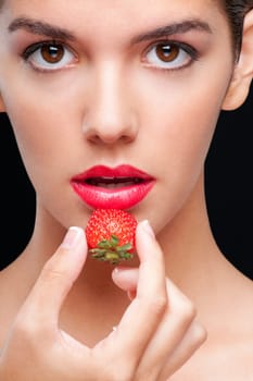 Portrait of a woman holding a strawberry
