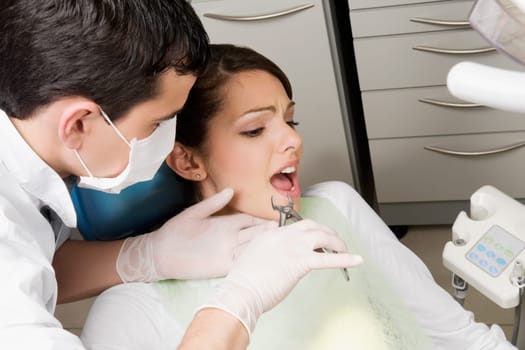 Dentist using pliers to pull out womanŽs teeth