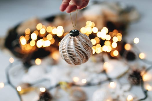 Hand is holding white Christmas tree toy. High quality photo