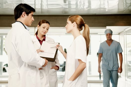 Three doctors discussing a clipboard