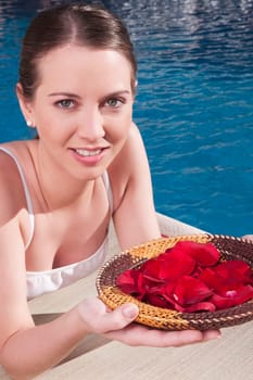 Woman holding a plate of rose petals at the poolside