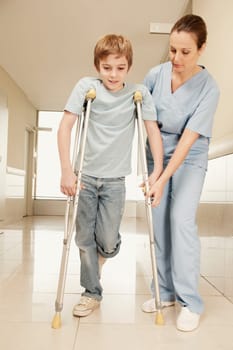 Female nurse assisting a boy on crutches