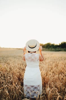 Girl in wheat field, girl's hand and wheat spikelet, sunset on field. High quality photo