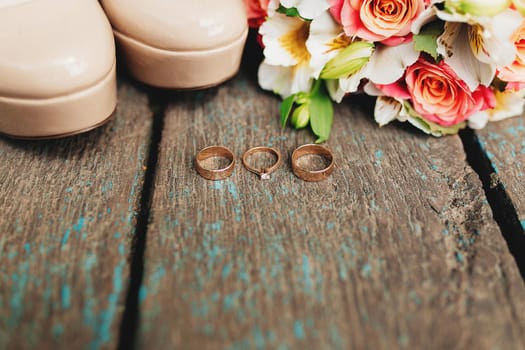 Wedding rings, shoes and bouquet on the wooden background. High quality photo