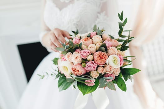 Bride in white dress is holding wedding bouquet. High quality photo