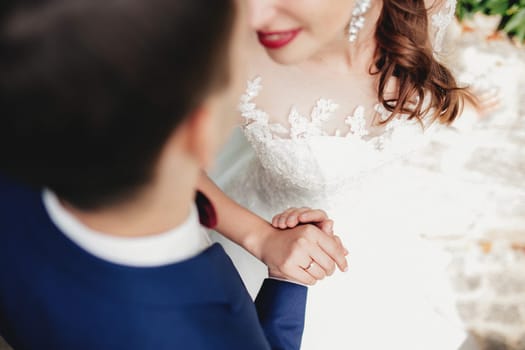 Groom holds bride hand in white dress. Bride is smiling. High quality photo