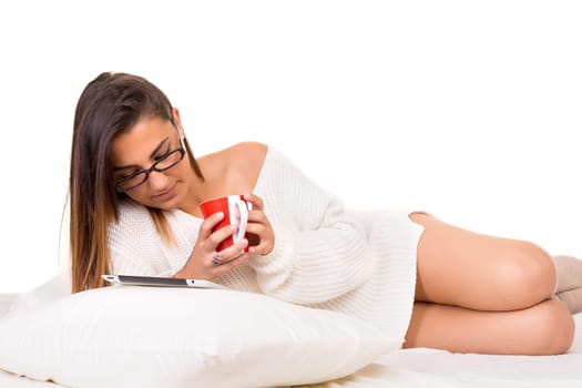 Young beautiful woman in bed, working or relaxing with her computer
