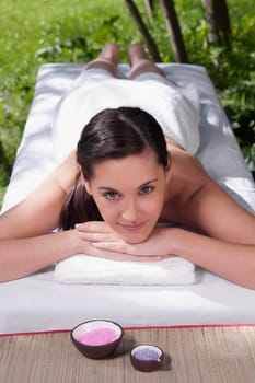 Portrait of a woman lying on a massage table with bath salt