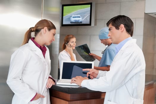 Two doctors discussing while using a laptop