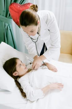 Girl on a hospital bed being examined by a female doctor