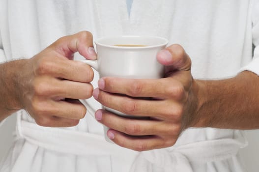 Mid section view of a man holding a cup of coffee