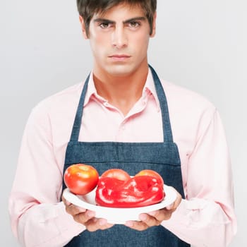 Man holding a plate of red bell peppers and tomatoes