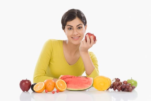 Portrait of a woman with a row of assorted fresh fruits