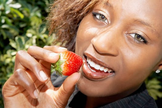 Woman holding a strawberry and smiling