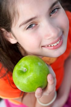 Portrait of a girl showing a granny smith apple and smiling
