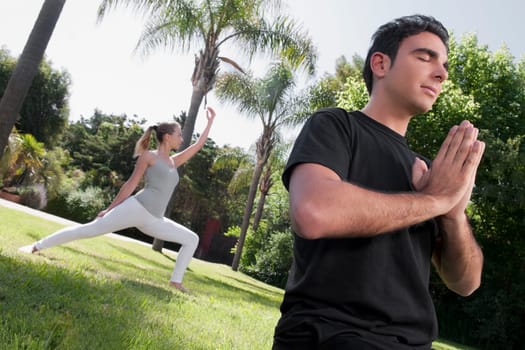 Couple practicing yoga in a park