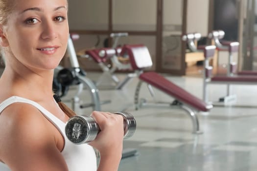 Portrait of a woman exercising with dumbbell in a gym