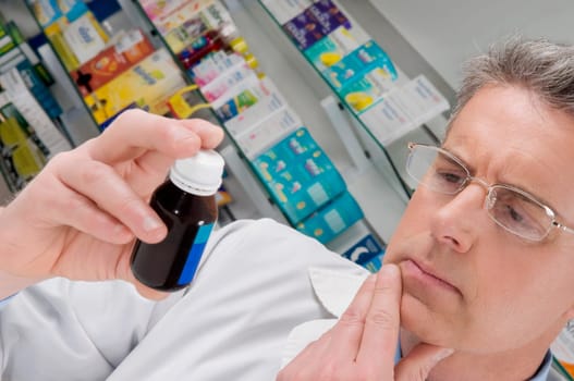 Pharmacist holding a medicine bottle and thinking