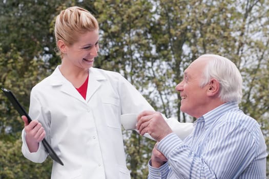Man drinking tea with a doctor standing beside him