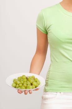 Mid section view of a woman holding a bowl of grapes