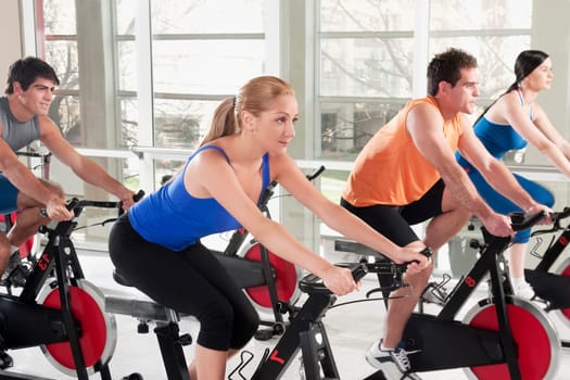 Men and women working out on exercise bikes in a gym