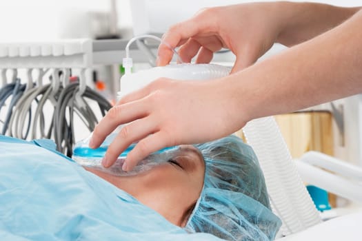 Anesthetist using an oxygen mask on a patient in a hospital