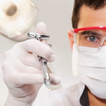 Close_up of a dentist holding a dental injection