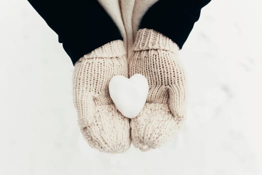 Snow heart snowball in girl gloved hands. Blurred background. High quality photo