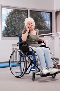 Disabled woman sitting in a wheelchair and talking on a mobile phone