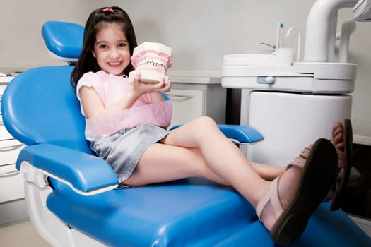 Portrait of a girl holding a set of dentures
