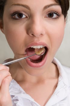 Woman examining her teeth with angled mirror