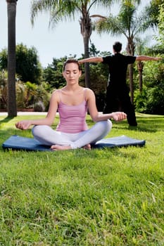 Couple practicing yoga in a park