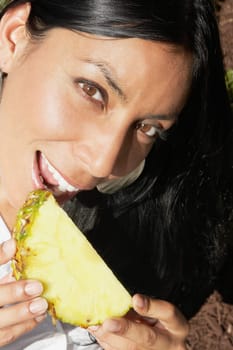 Portrait of a woman eating a slice of a pineapple