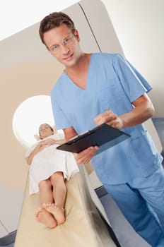 Surgeon checking medical report with a patient undergoing an MRI scan in background