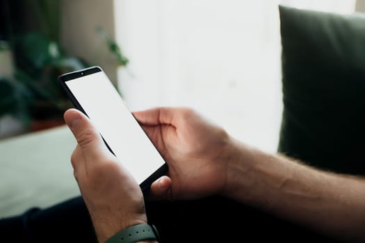 Man is holding smartphone with white screen. Blurred background. High quality photo
