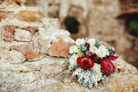 Wedding bouquet on the broken brick fence. Blurred background. High quality photo