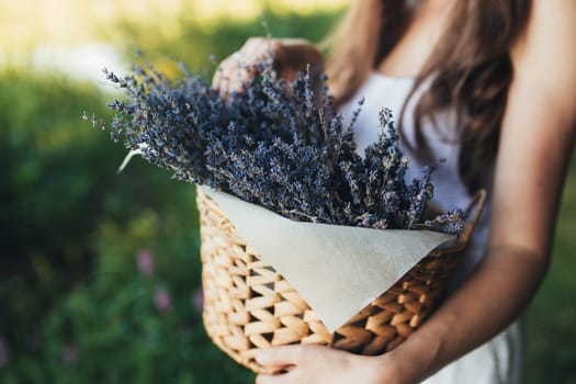 Girl is holding purple lavender flowers in the wooden box. High quality photo