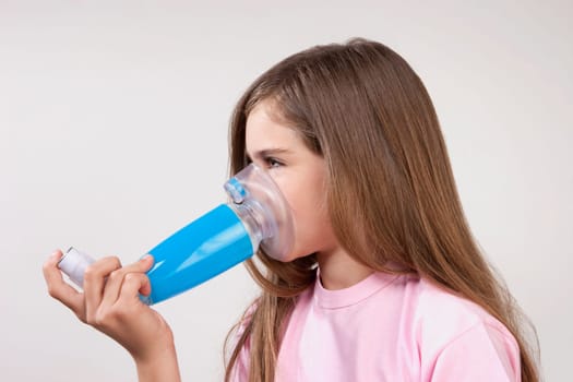 Girl using an asthma inhaler attached with a spacer