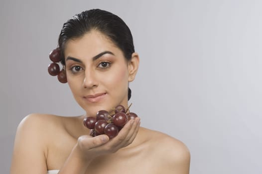 Portrait of a woman holding a bunch of red grapes