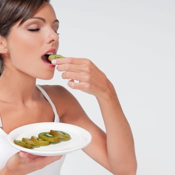 Woman eating sliced kiwi fruit