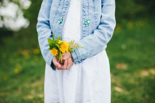 Small girl is holding yellow chamomile flowers. High quality photo