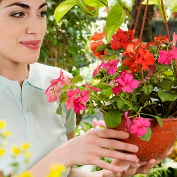 Woman holding a hanging basket in a greenhouse