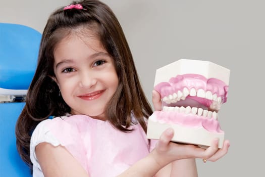 Portrait of a girl holding a set of dentures