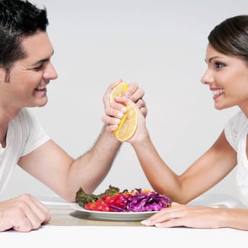 Couple squeezing orange halves over a salad