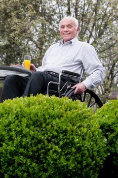 Portrait of a man sitting in a wheelchair and holding a glass of juice