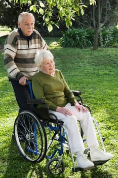 Man pushing his disabled wifeŽs wheelchair in a garden
