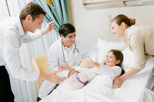 Girl on a hospital bed and her parents discussing with a doctor